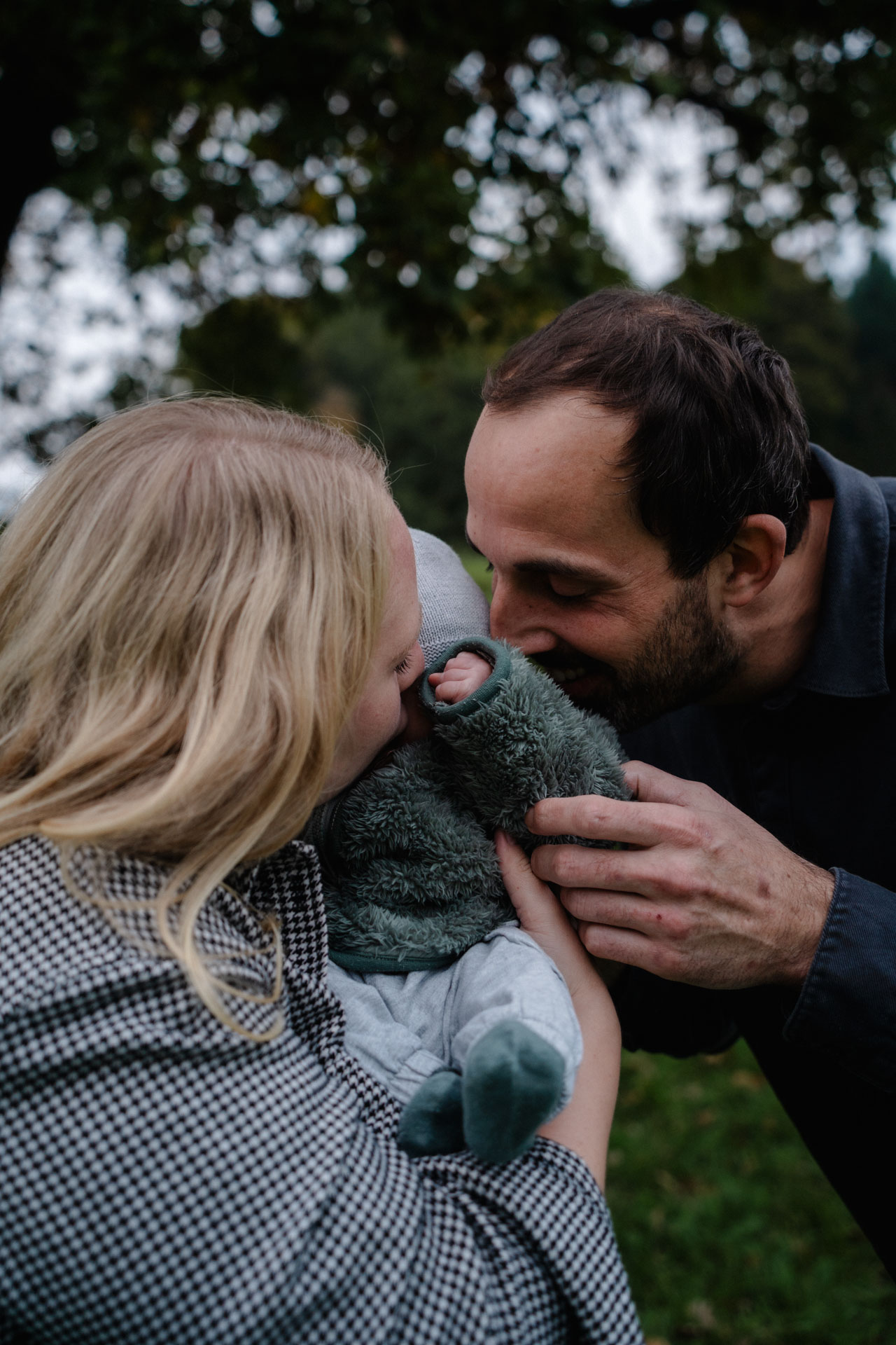 Vater und Mutter knuddeln ihr Kind, das Foto ist im Rahmen der Newborn- und Familienfotografie entstanden.