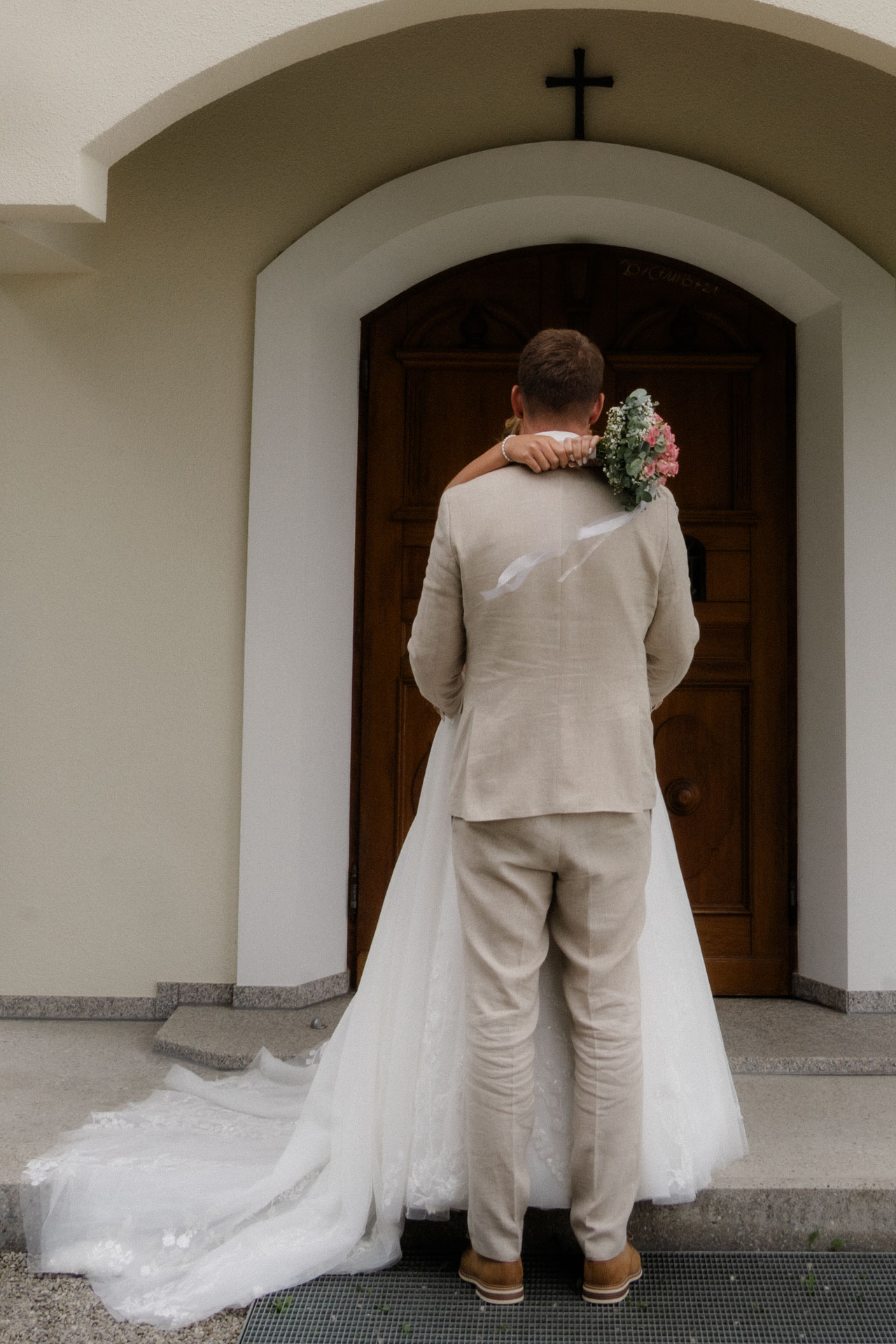 Ein sehr ästhetisches Foto von Braut und Bräutigam vor einer Kapelle.