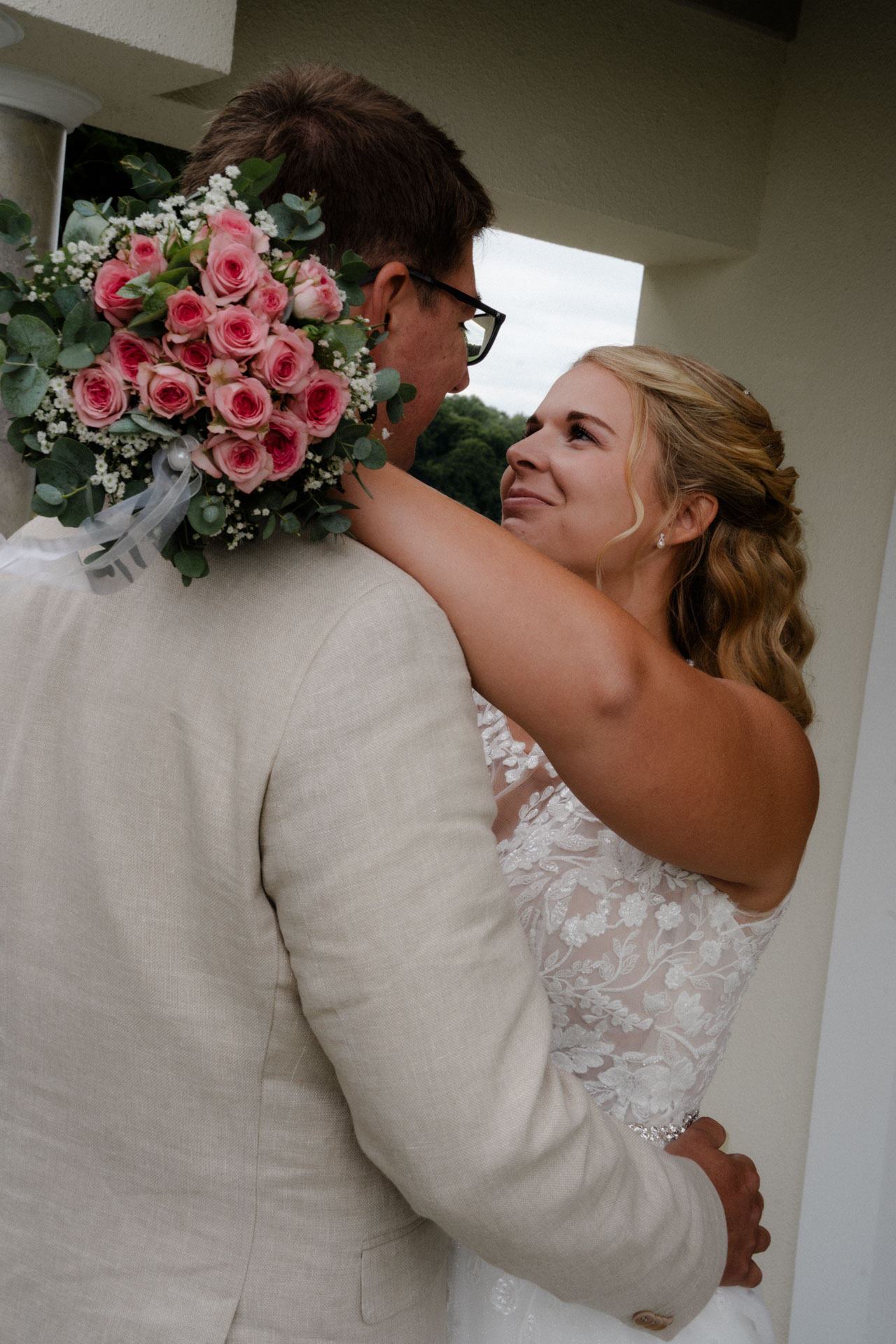 Die Braut hat die Arme um ihren Bräutigam geschlungen.