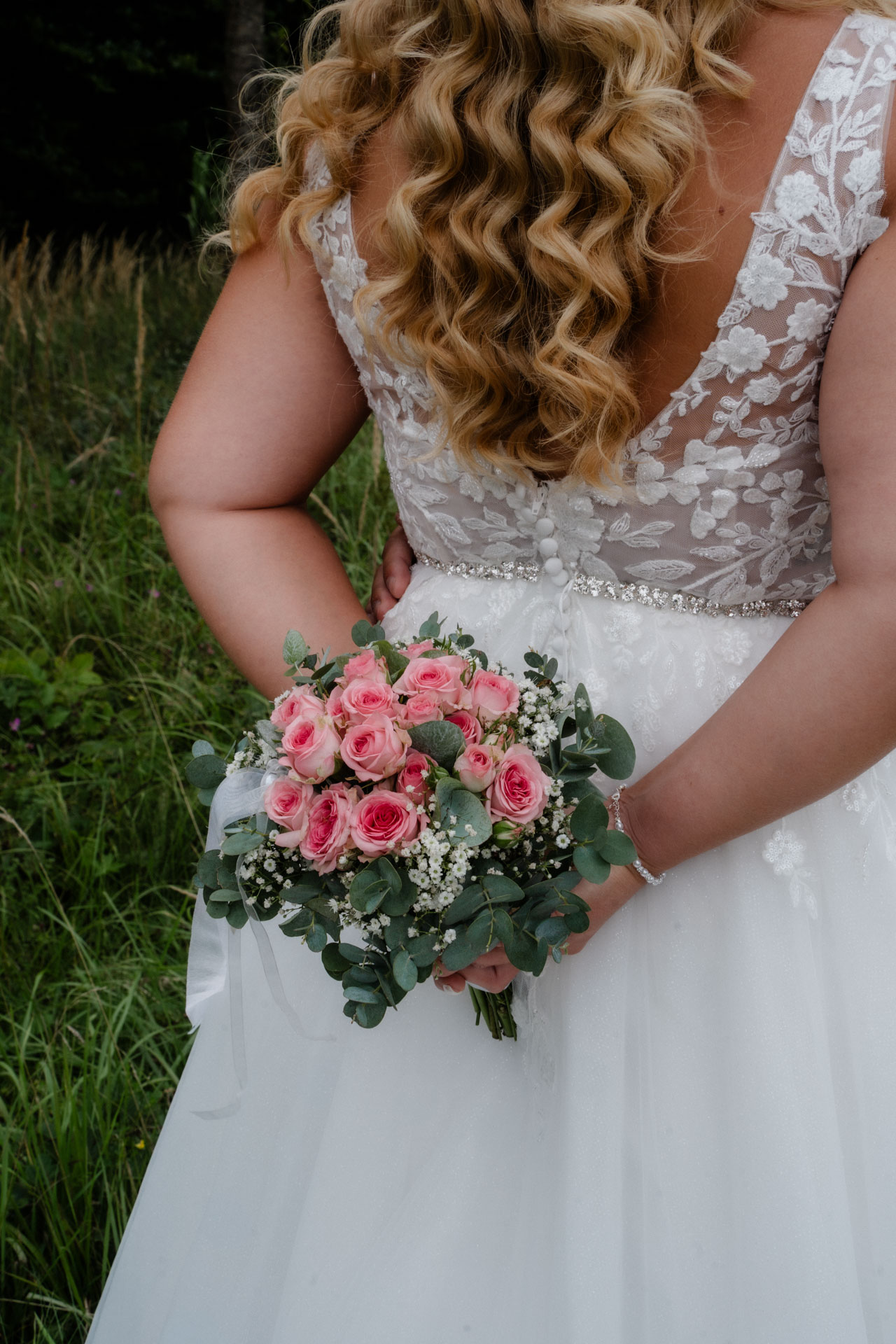 Die Braut von hinten, die einen Brautstrauß hält.
