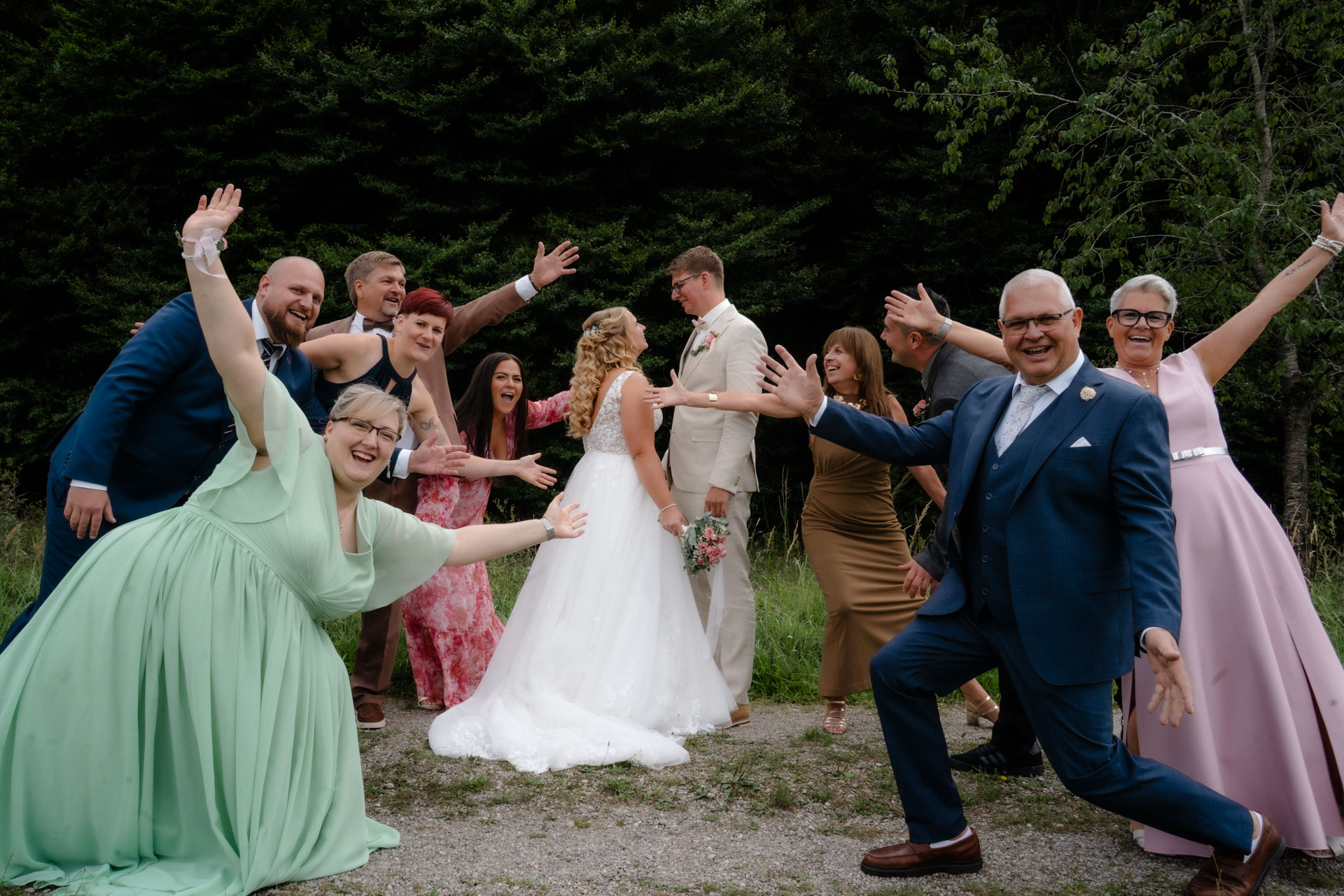 Die Familien von Braut und Bräutigam und wie sie in die Kamera jubeln, während sich das Ehepaar ansieht.