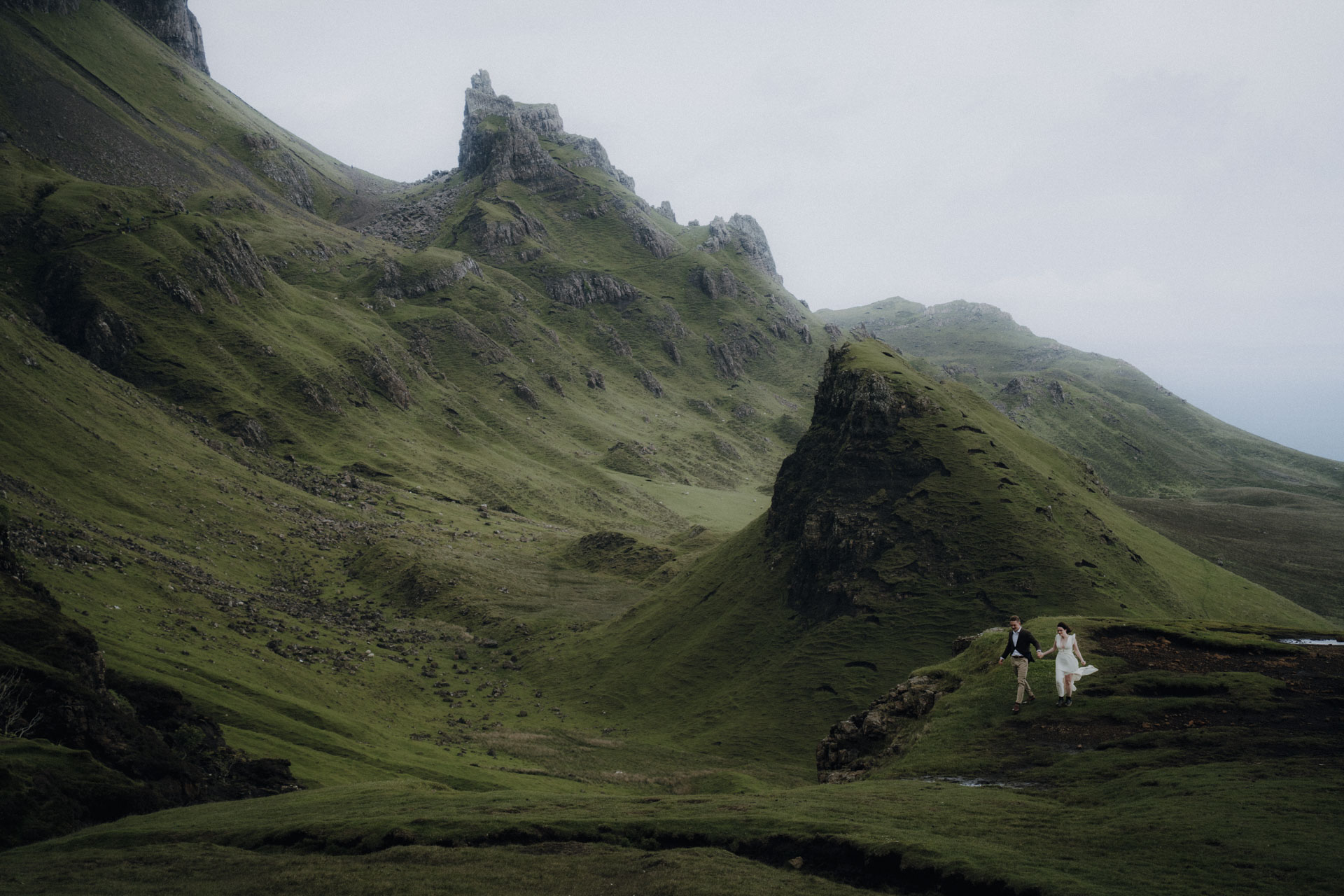 Die Hochzeitsfotografin hat das Brautpaar hier auf dem Quiraing in Schottland, auf der Isle of Skye fotografiert, sie sind klein zu sehen während der Fokus auf der atemberaubenden Landschaft liegt