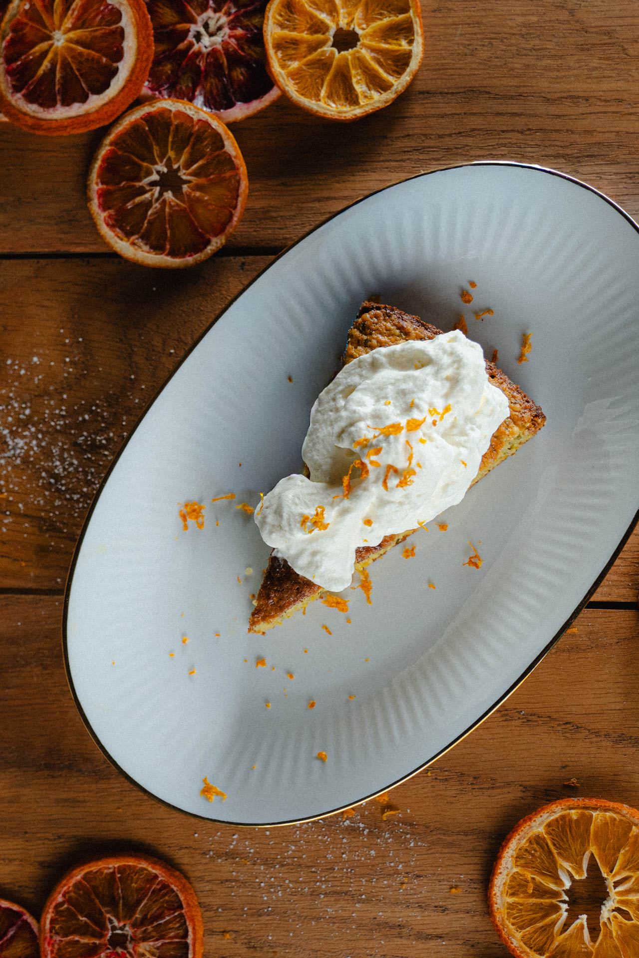 Das Foto eines Orangenkuchens, stilvoll arrangiert auf einem Tisch mit getrockneten Orangenscheiben, das Foto ist im Rahmen der Produkt-, Werbe und Foodphotography entstanden.