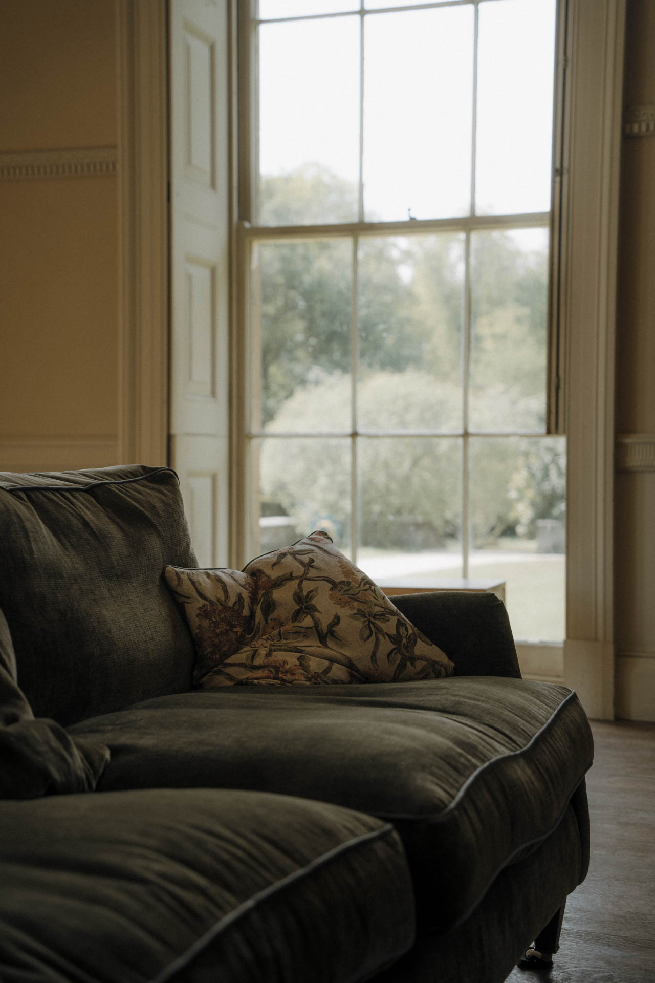 Ein Sofa vor einem großen Sprossenfenster, das Foto ist im Rahmen der Hotelfotografie entstanden
