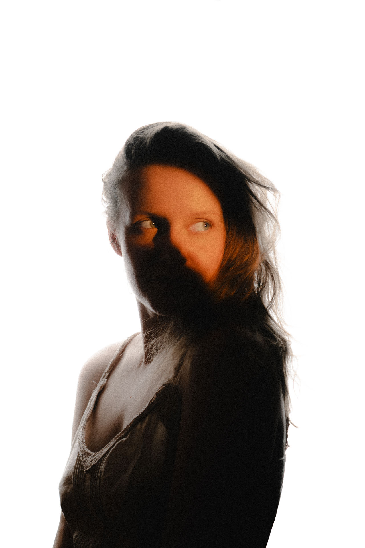 Portraitfoto einer Frau, eine Seite ist in orangenen Tönen kunstvoll beleuchtet