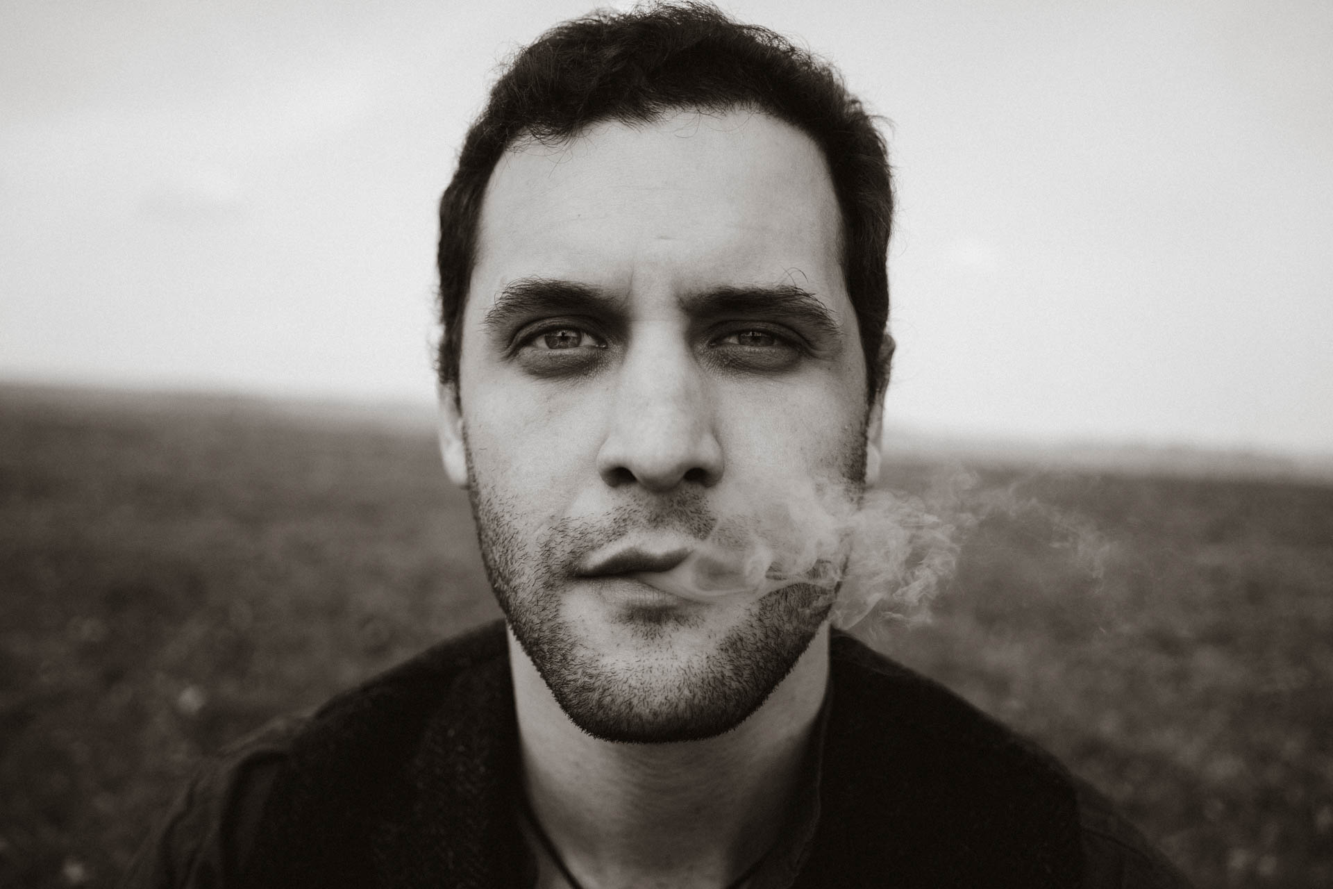 Künstlerportrait eines Mannes mit Zigarre, in monochrom gehalten, das Foto ist im Rahmen der Portraitfotografie entstanden