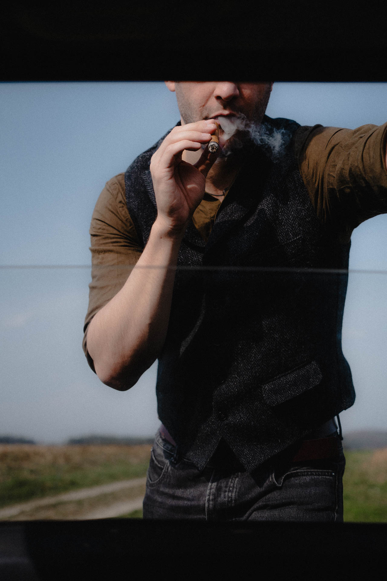 Das Portrait eines Mannes, der eine Zigarre raucht. Das Foto ist altmodisch und nostalgisch und wirkt analog.