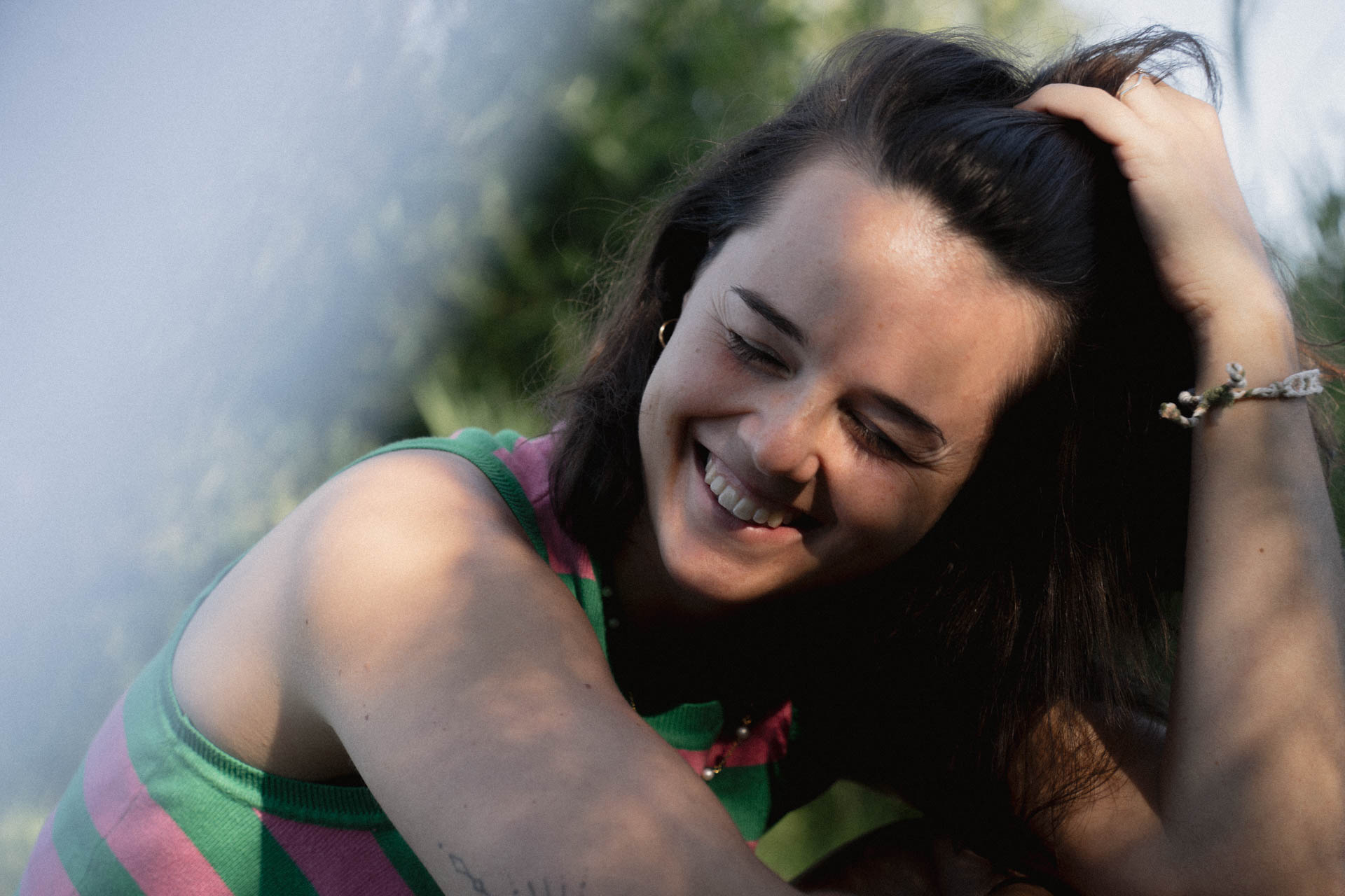 Eine Frau streicht sich durch die Haare und grinst. Das Foto ist im Rahmen der Portraitfotografie entstanden.