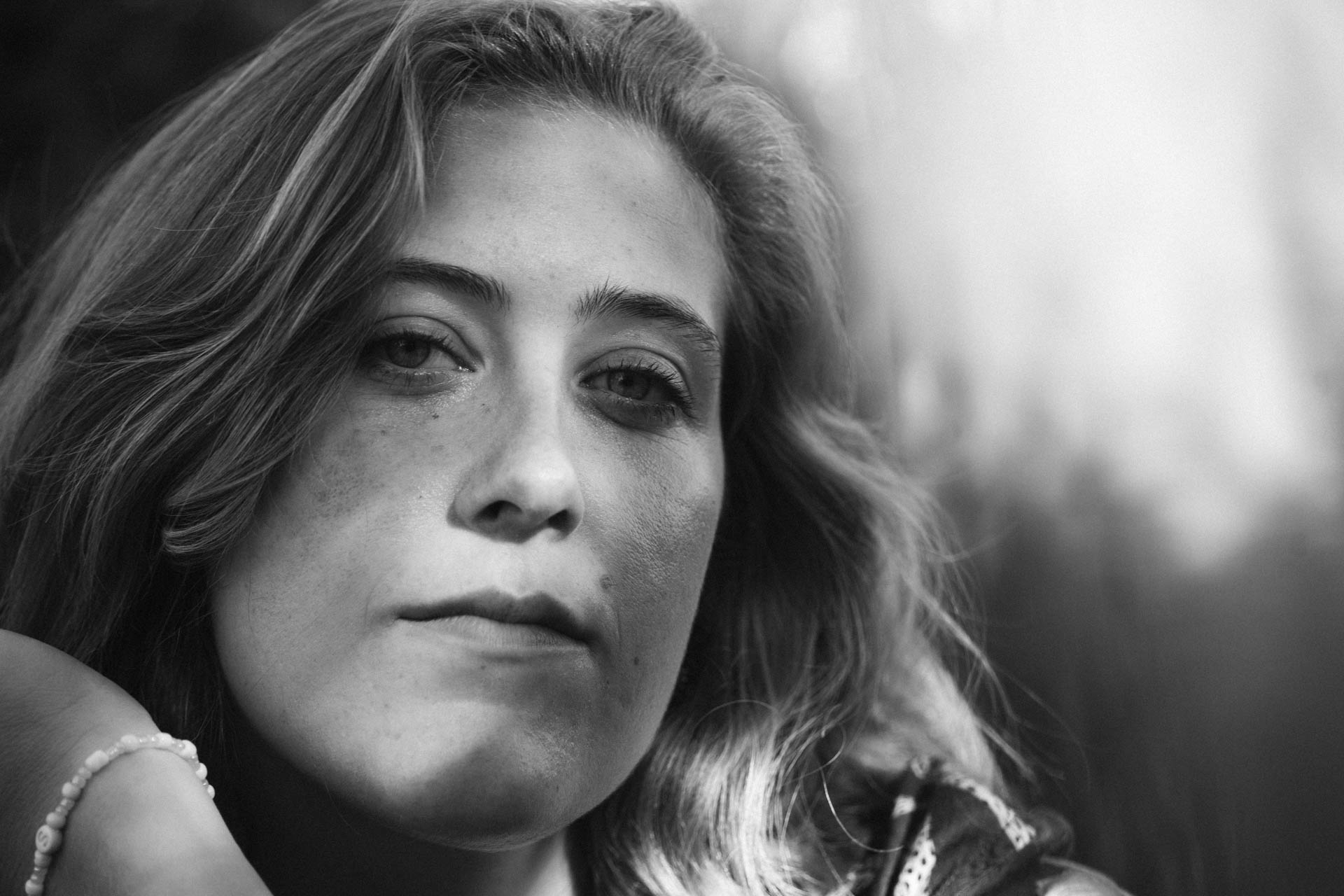 Das monochrome Foto einer Frau, die in die Kamera lächelt. Das Foto ist im Rahmen der Portraitfotografie entstanden.