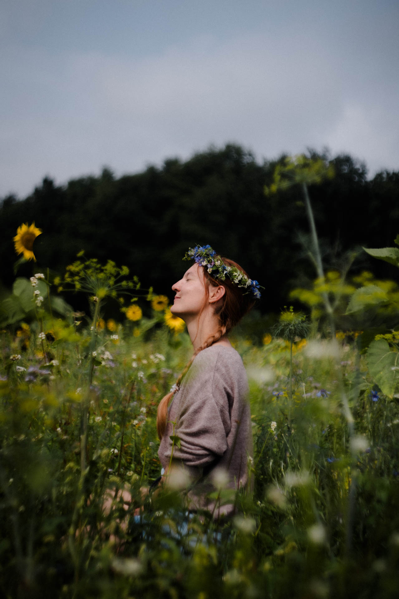 Eine Frau in einer Blumenwiese, die in die Sonne lächelt. Das Foto ist im Rahmen der Portraitfotografie entstanden.