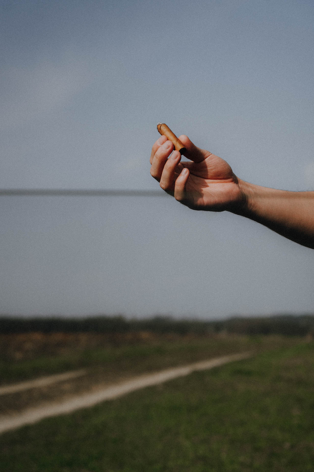 Eine Hand, die eine Zigarre hält, durch ein Autofenster fotografiert, das Foto ist im Rahmen der Portrait- und Businessfotografie entstanden
