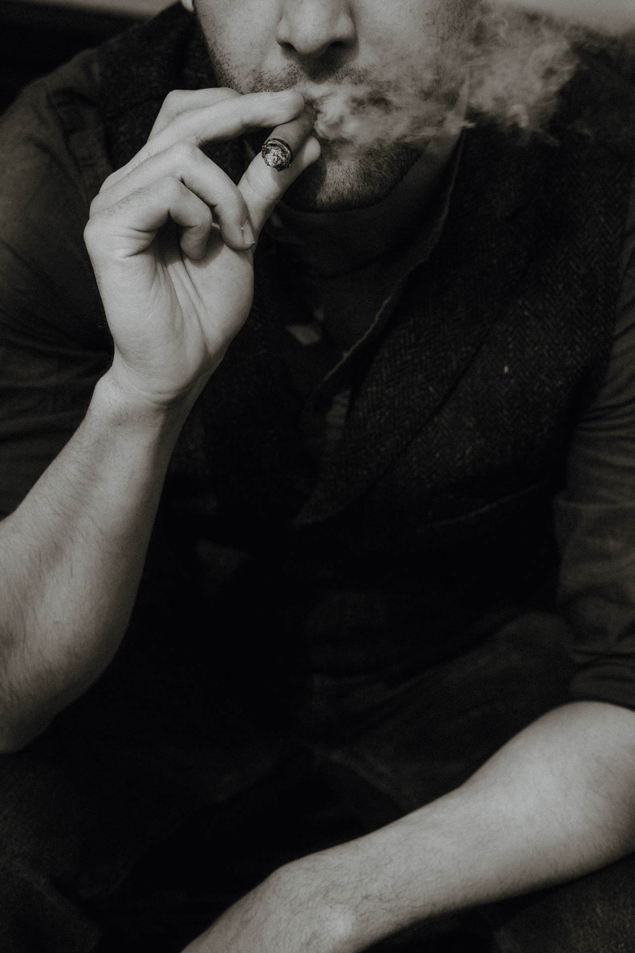 Das Portrait eines Mannes, der eine Zigarre raucht. Das Foto ist altmodisch und nostalgisch und wirkt analog.