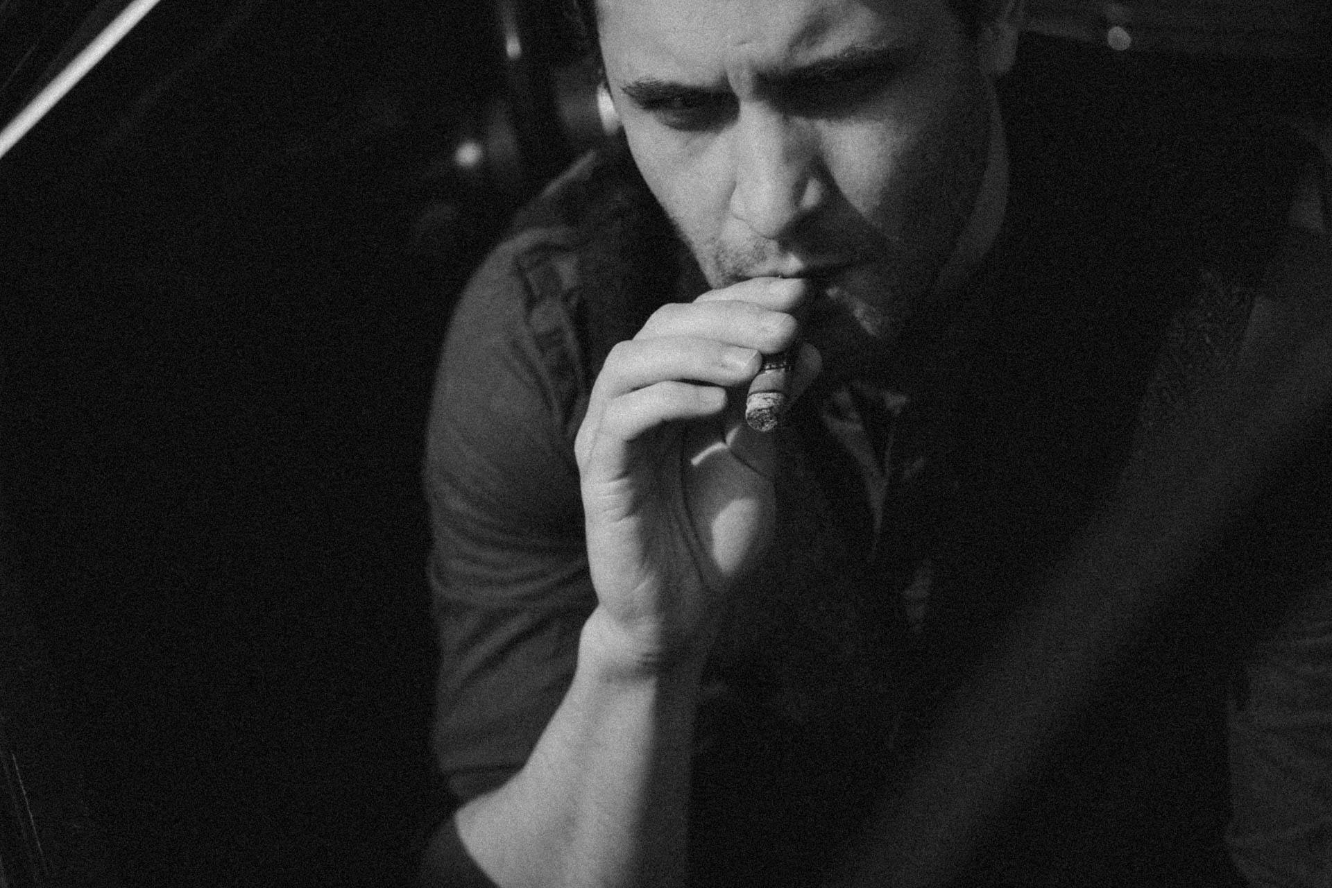 Das Portrait eines Mannes, der eine Zigarre raucht. Das Foto ist altmodisch und nostalgisch und wirkt analog.