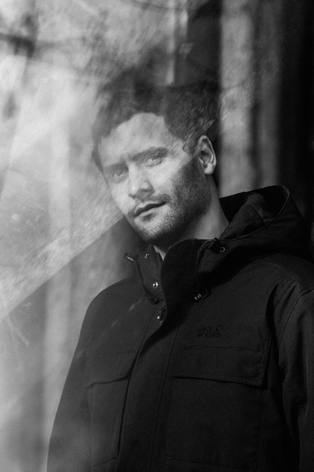 Das monochrome Foto eines Mannes, künstlerisch in Szene gesetzt. Das Foto ist im Rahmen der Portraitfotografie entstanden.