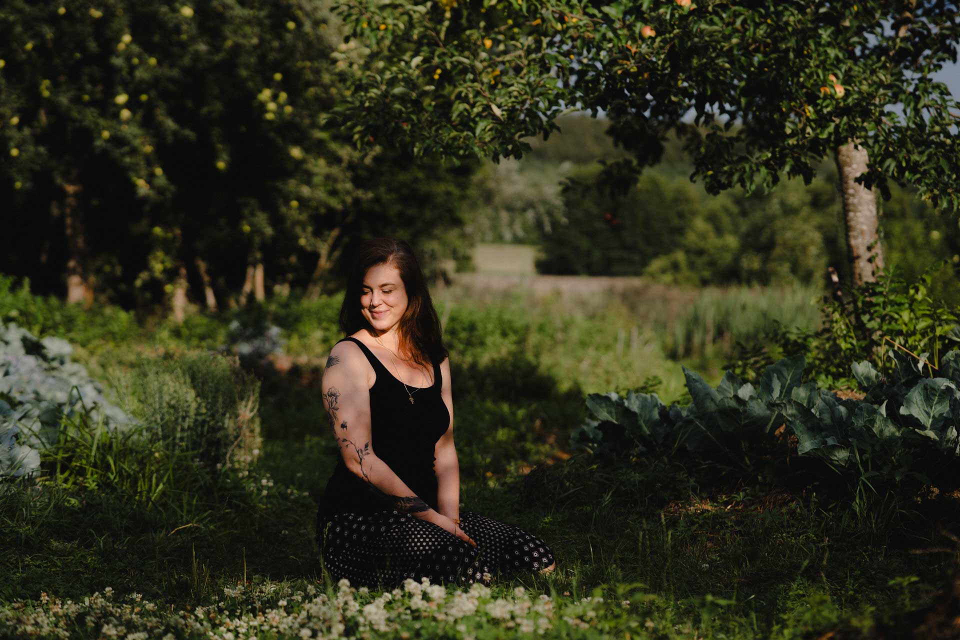 Eine Frau die auf der Wiese sitzt, die Sonne scheint ihr ins Gesicht, das Foto ist im Rahmen der Business- und Portraitfotografie entstanden.