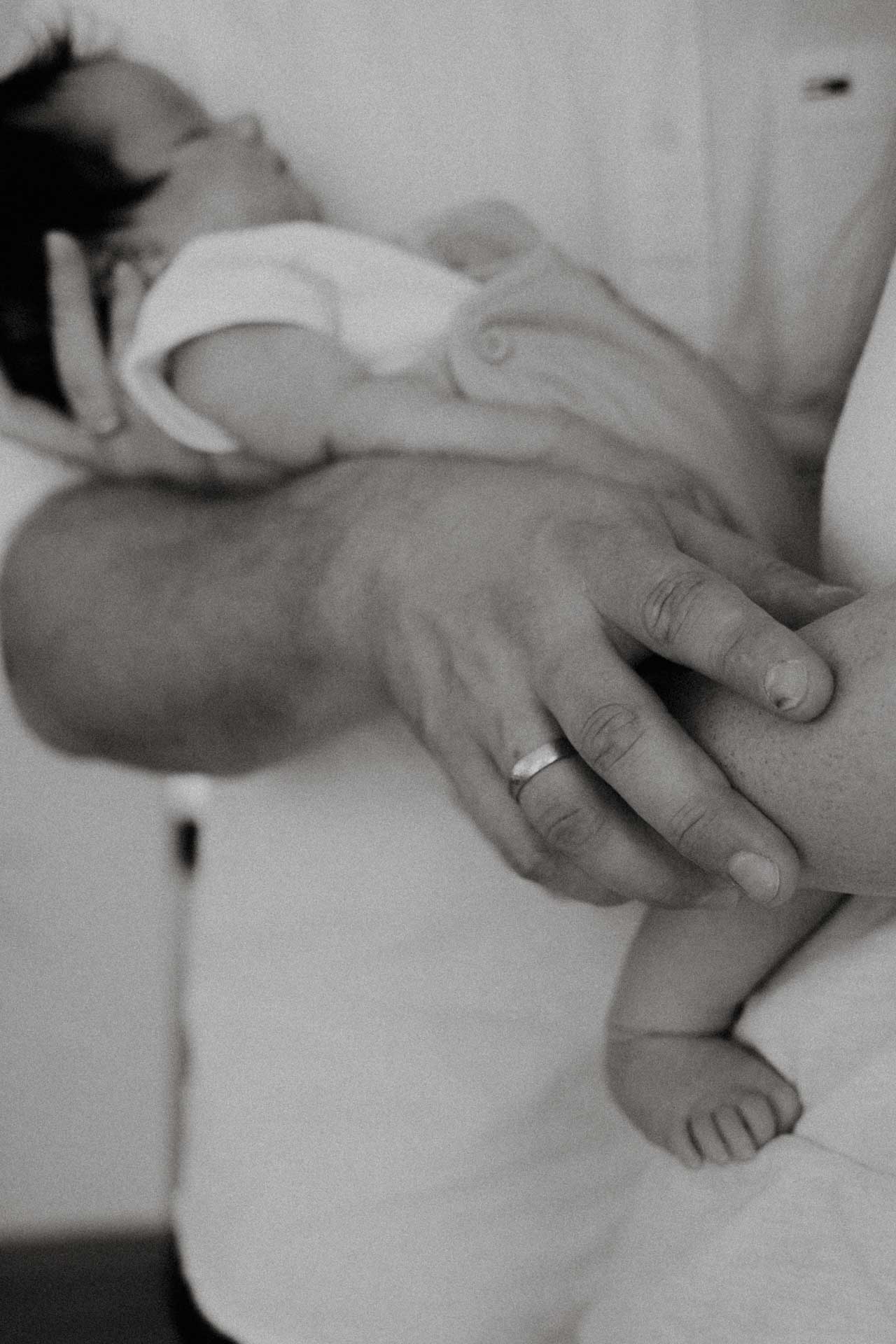 Ein Vater trägt seine Tochter, das Foto ist im Rahmen der Newbornfotografie entstanden